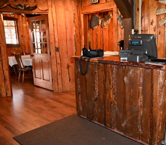 Rustic wood-paneled interior featuring a prominent reception counter with a live-edge wood top, wood-finish flooring, and a paneled door with glass inserts leading to an additional space
