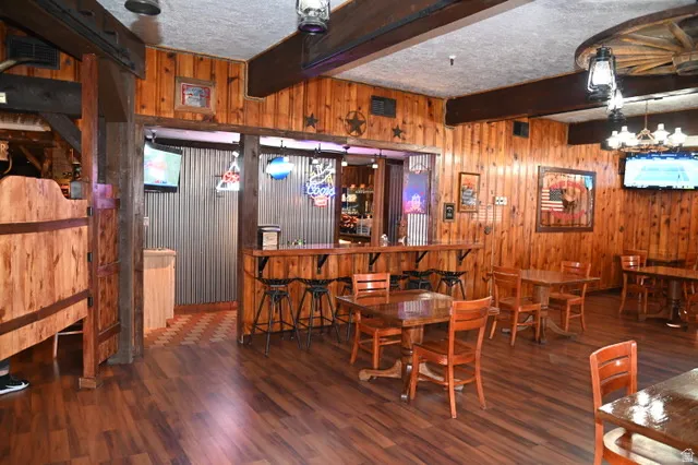 Spacious interior featuring extensive wood paneling, wood-finish flooring, and exposed ceiling beams