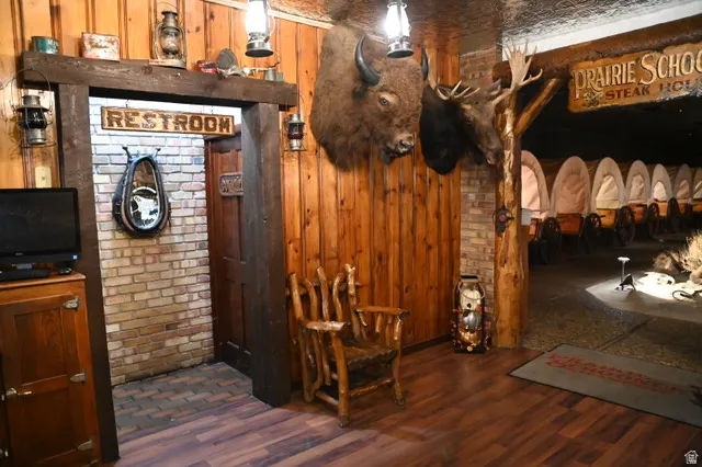 Wood-finish flooring throughout, complemented by wood-paneled walls and exposed brick accents
