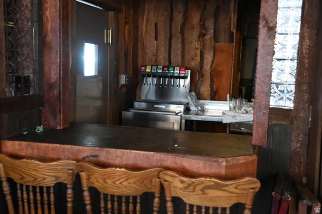 Rustic-style bar area featuring a substantial wood-finish countertop, wood plank wall paneling, and decorative glass block accents