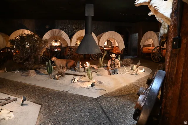 Themed interior space featuring multiple covered wagon installations, a central free-standing fireplace with a conical hood, and a simulated desert landscape with various decorative elements