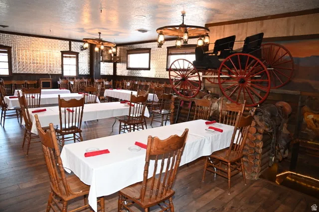 Spacious dining area featuring wood-finish flooring, pressed tin wall panels, and exposed wood beams