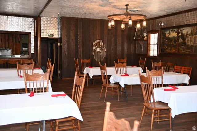 Spacious room featuring wood-finish flooring, dark wood paneling, and textured ceiling panels