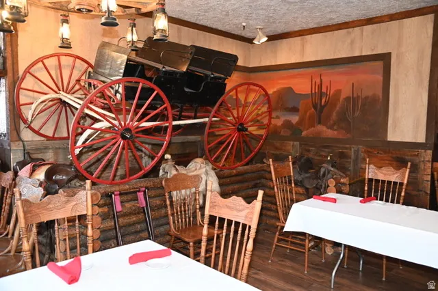 Interior space featuring a wagon display with red spoked wheels, rustic wood paneling, a large desert mural, and lantern-style light fixtures