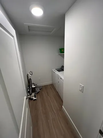 Dedicated laundry area featuring wood-finish flooring, white walls, and a recessed ceiling light