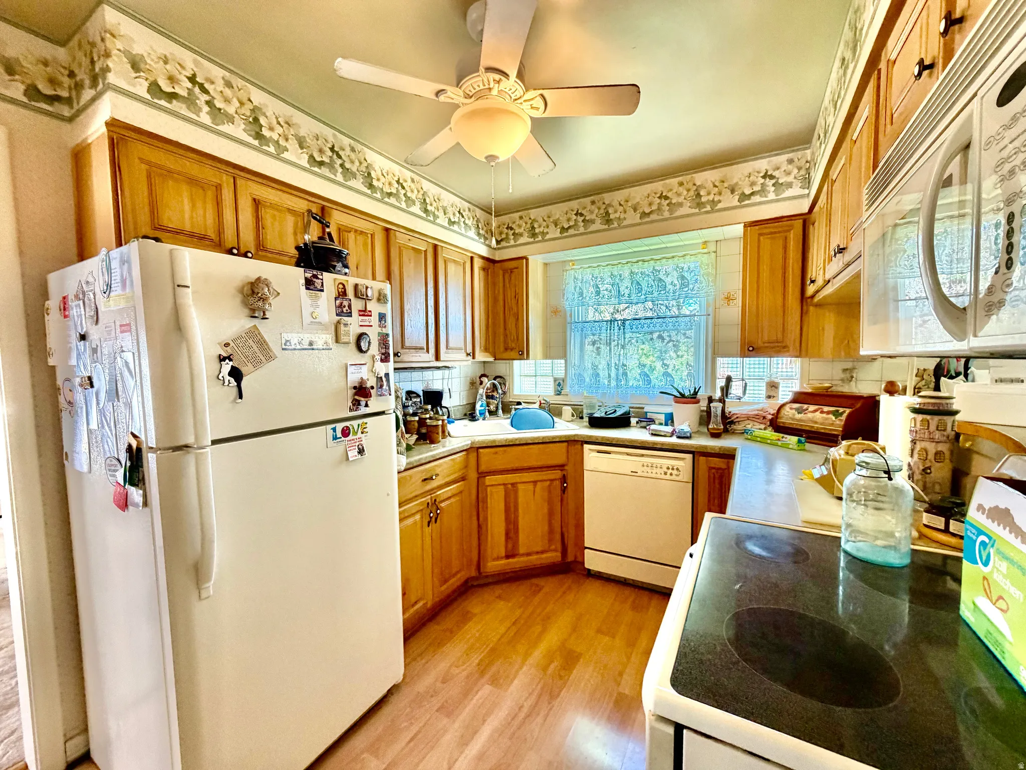 Kitchen featuring wood-finish flooring, wood cabinetry, built-in microwave, and a ceiling fan with integrated lighting