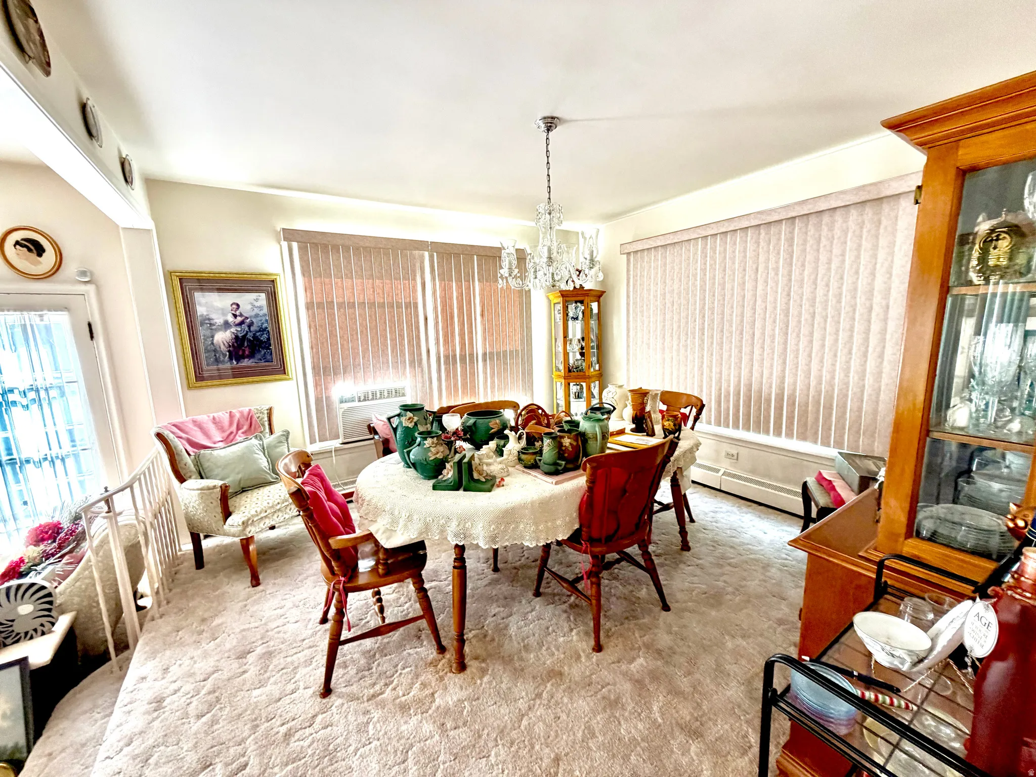 Dining area featuring a crystal chandelier, vertical blinds, and light-toned carpet flooring