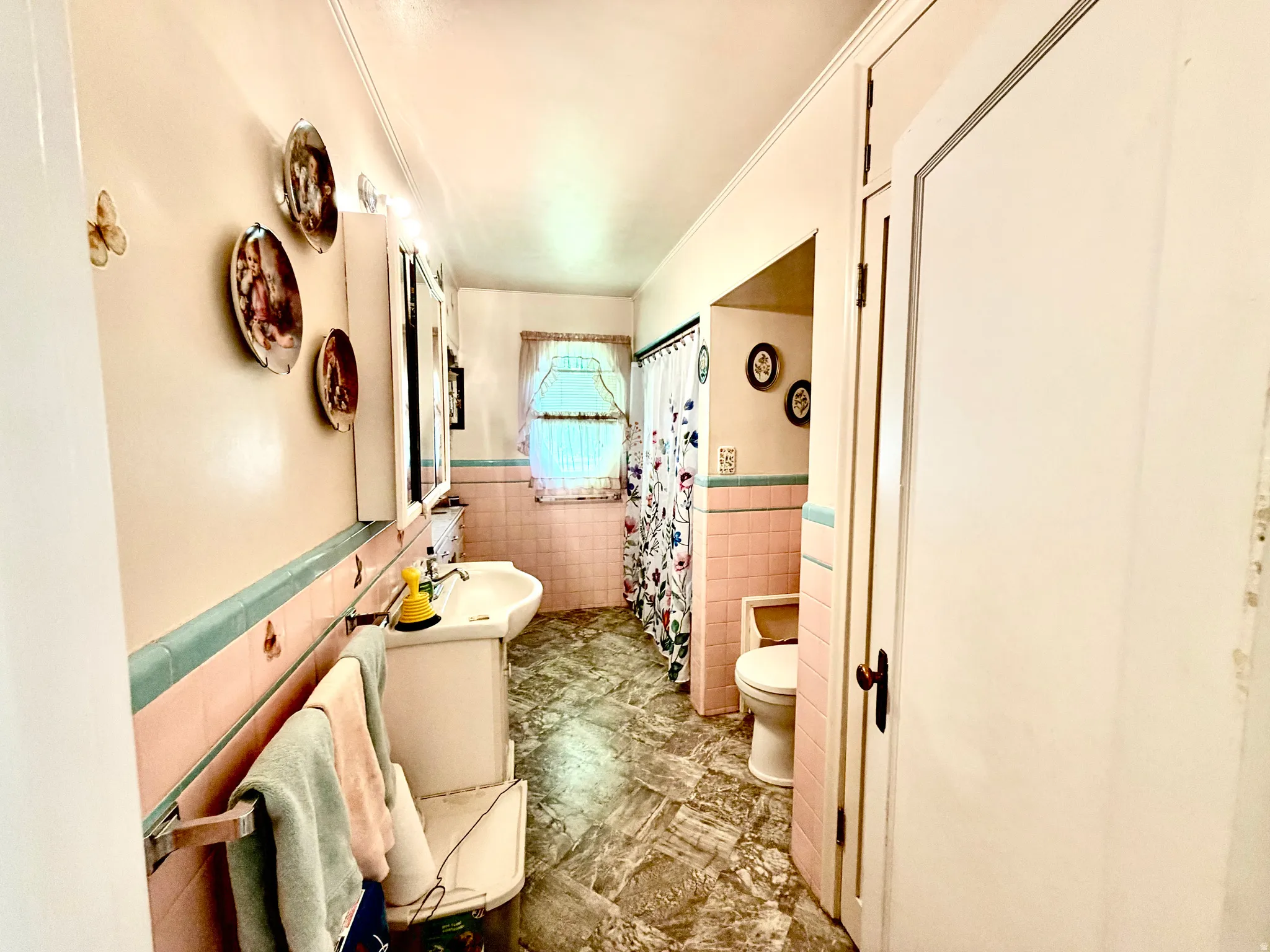 Bathroom featuring a pedestal sink, tiled walls, a window with privacy curtains, and a built-in medicine cabinet