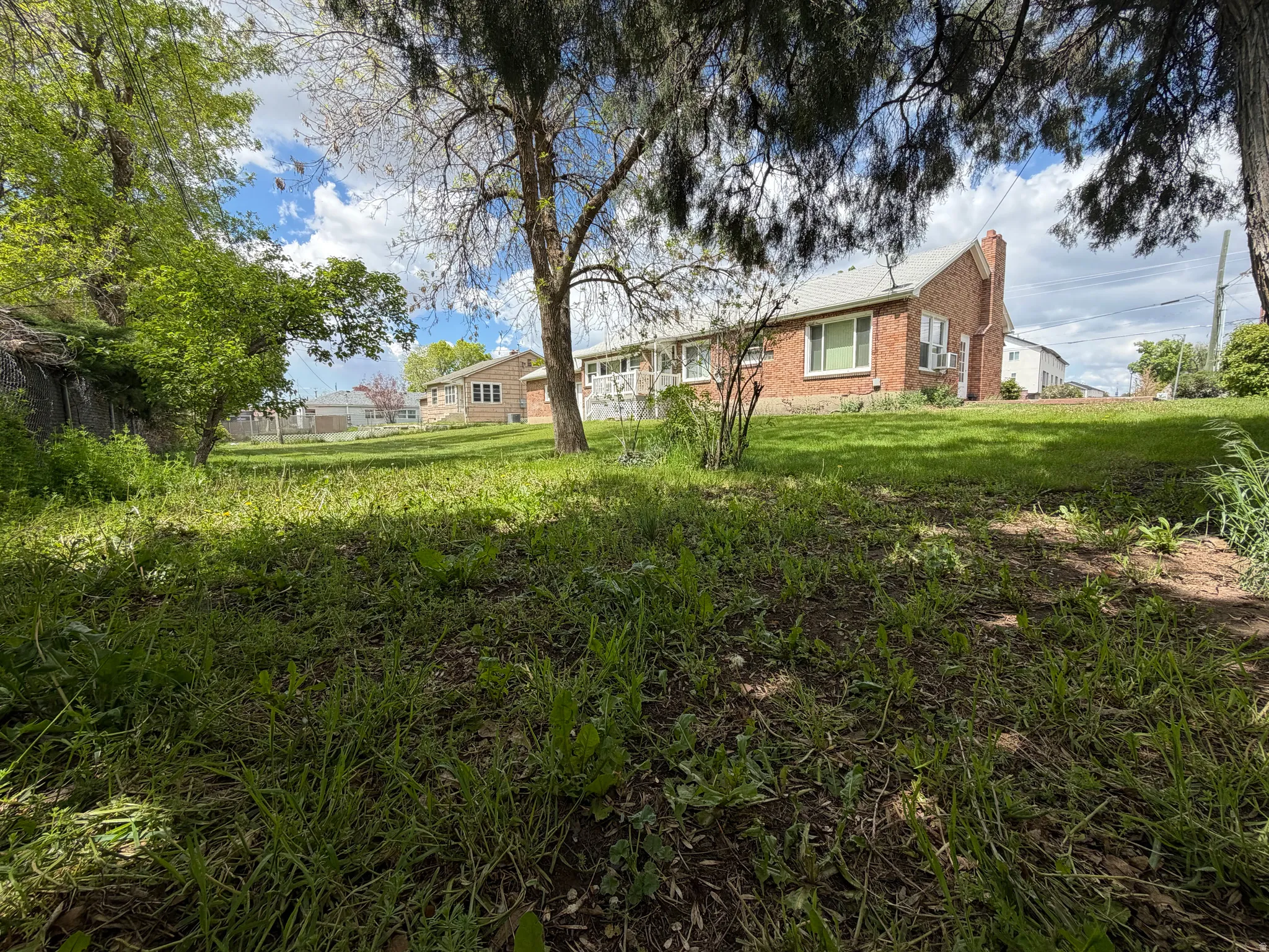 Expansive outdoor space featuring a sloped lawn and mature trees