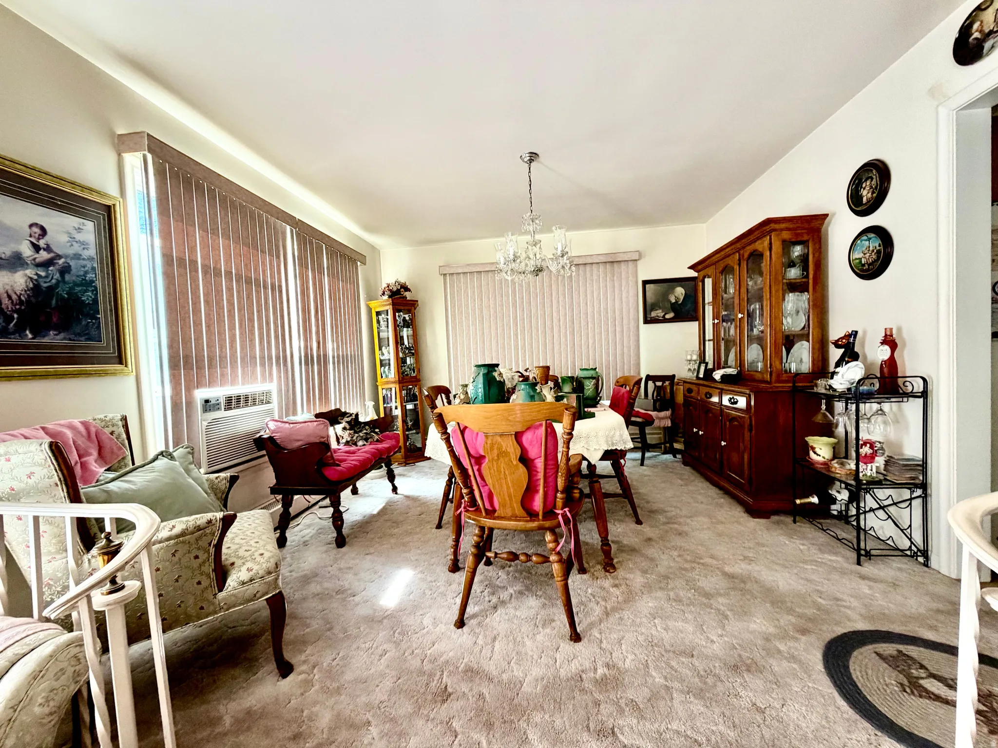 Open room featuring textured carpeting, vertical window blinds, and a chandelier lighting fixture