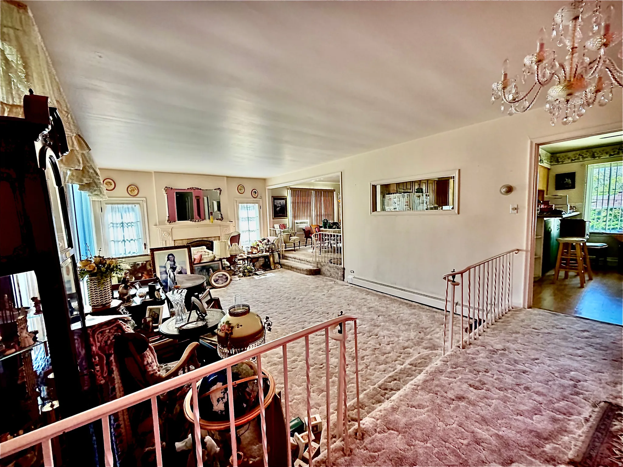 Living area featuring a textured carpeted floor, white walls, and a decorative crystal chandelier