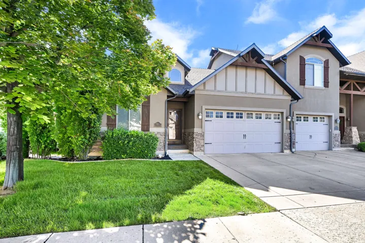 Stucco and stone facade with a 2-car garage, architectural gables, and a landscaped front yard