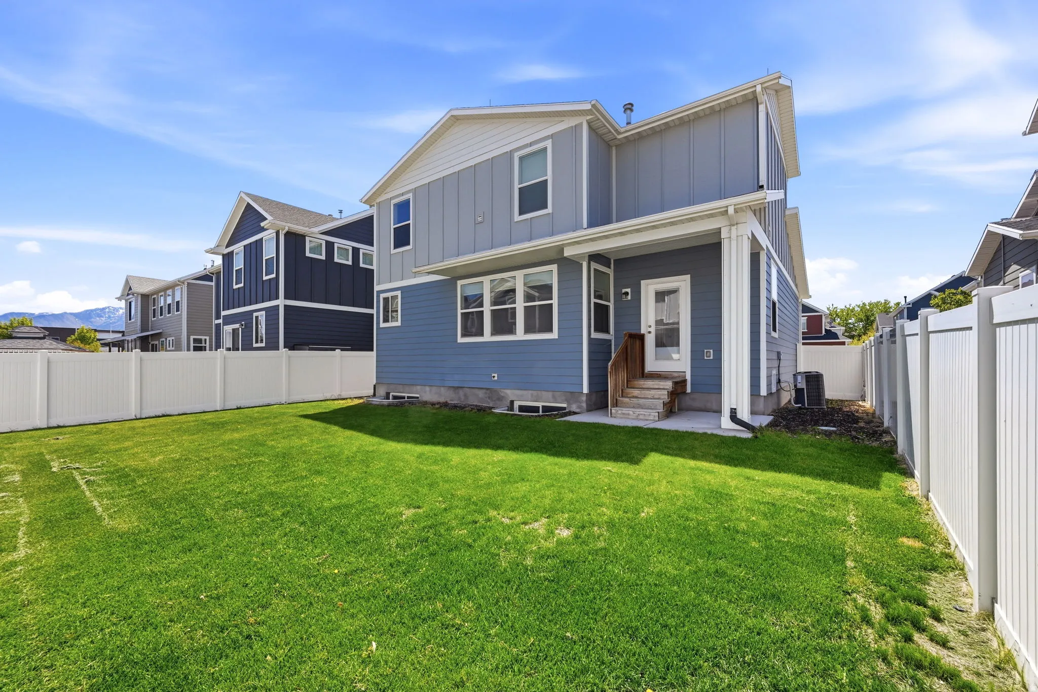 Back of property with board and batten siding, a fenced backyard, and entry steps
