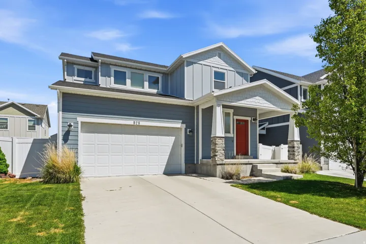 Craftsman-style home with covered porch, driveway, an attached garage, stone siding, and board and batten siding