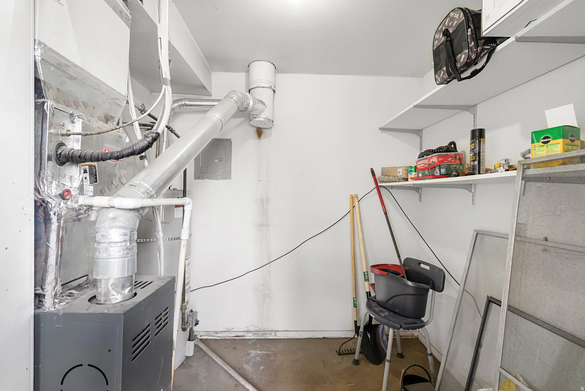 Utility area featuring a furnace system with associated ductwork and shelving