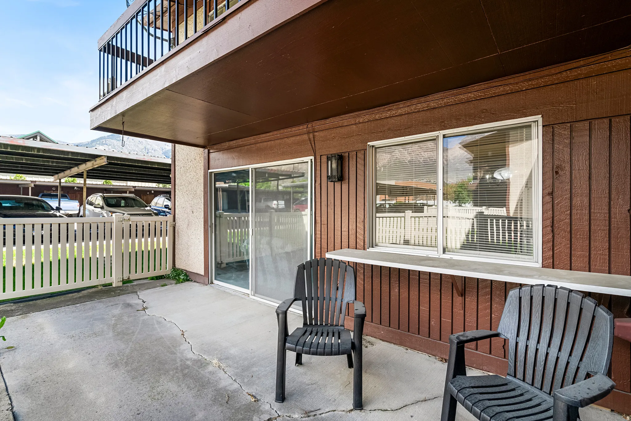 Private concrete patio featuring a lower privacy fence and an upper balcony