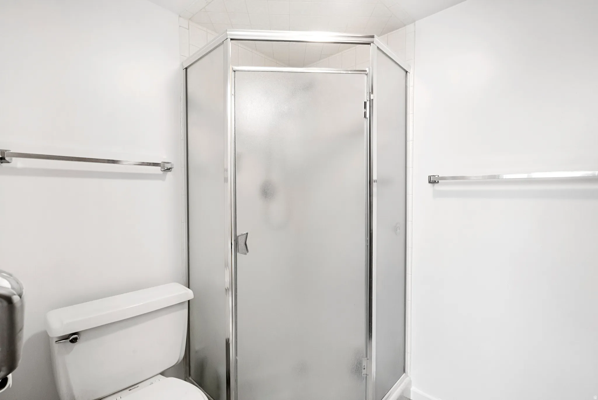 Corner shower with frosted glass enclosure and chrome framing