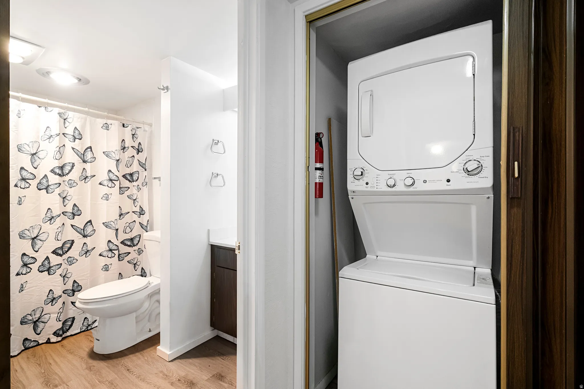 In-unit stackable washer and dryer, wood-finish flooring, and a vanity with a dark wood-finish cabinet and solid surface countertop