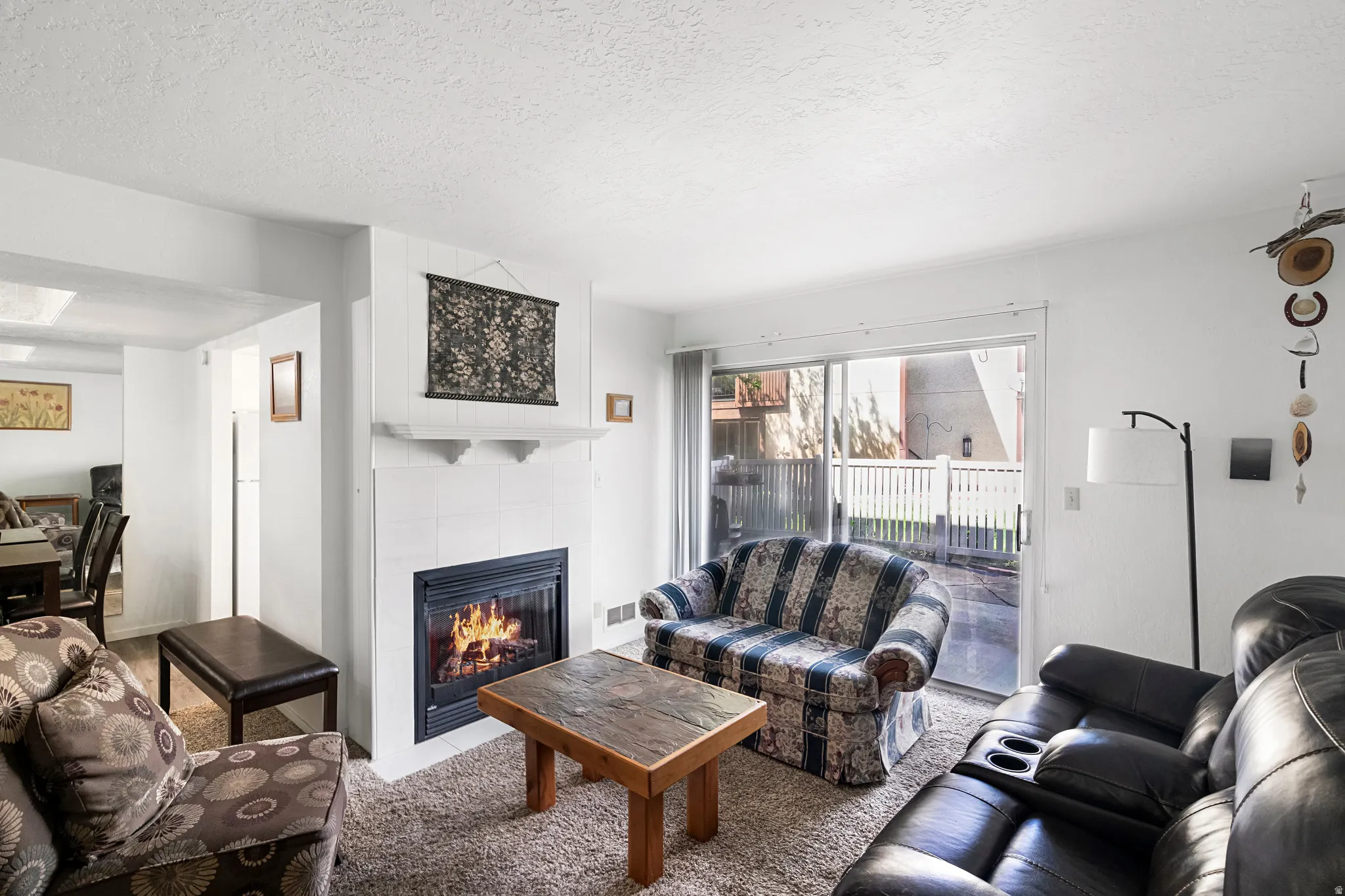 Living area featuring a tiled fireplace with a mantel, carpeted flooring, and a sliding glass door