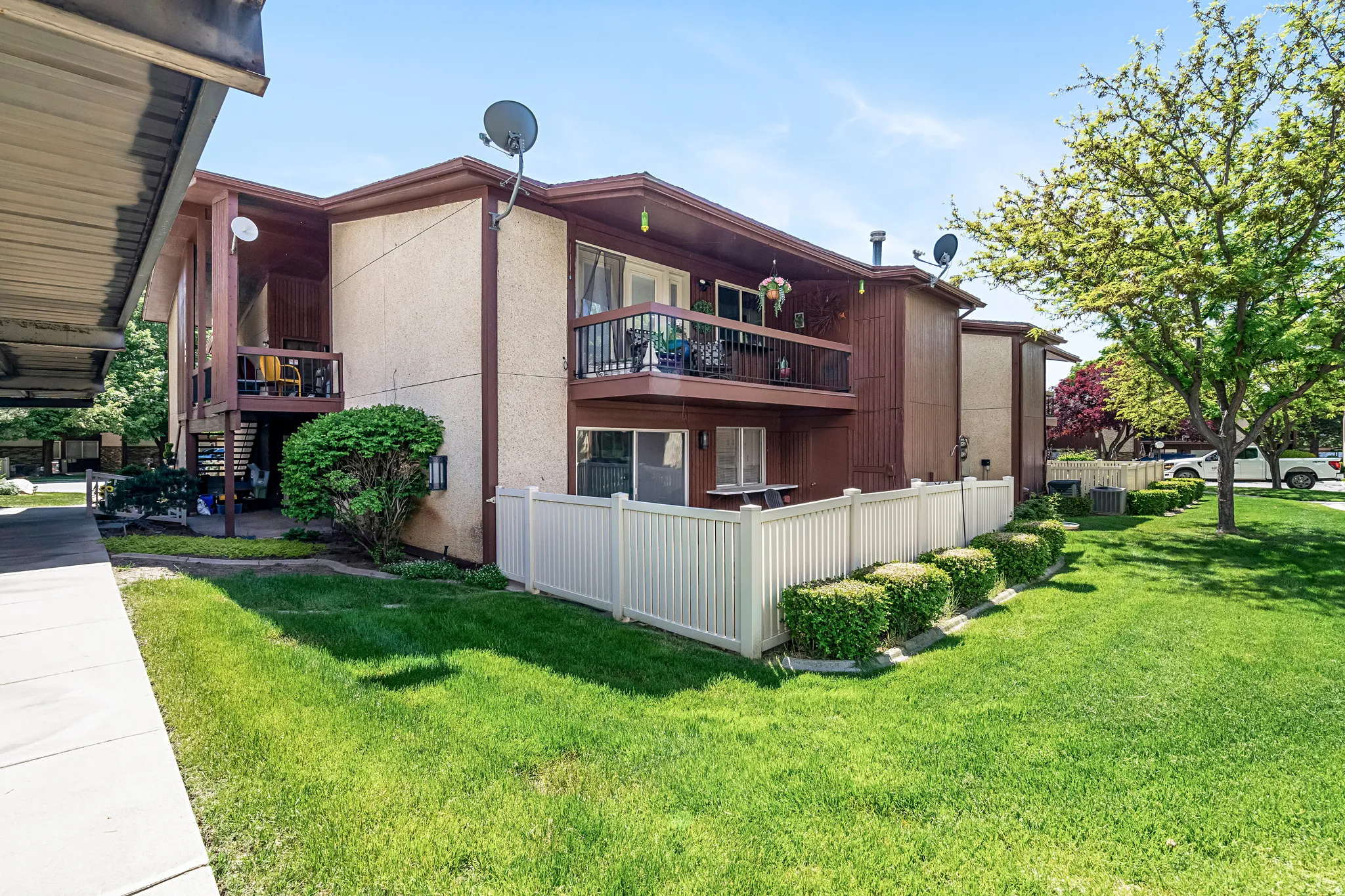 Multi-level exterior featuring balconies, a patio, and a white privacy fence