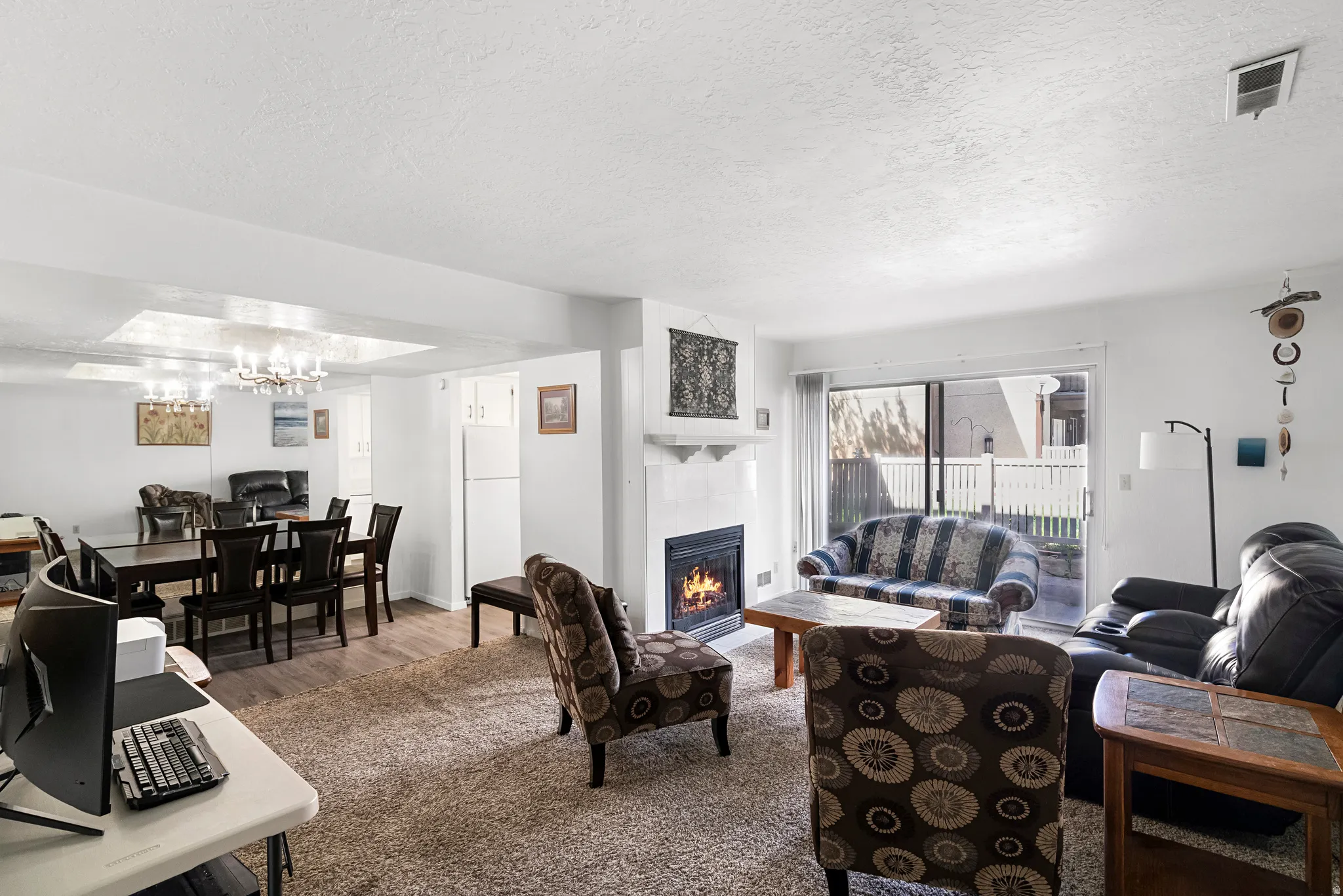Living area featuring a fireplace with a white mantel, light-toned carpet, and glass sliding doors