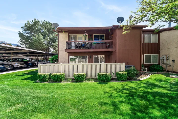 Two-story multi-unit dwelling featuring a second-floor balcony, ground-level patio, and a privacy fence