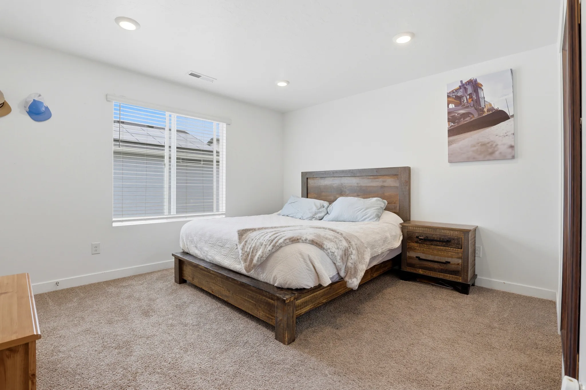 Bright bedroom featuring recessed lighting, a window with horizontal blinds, and carpeting
