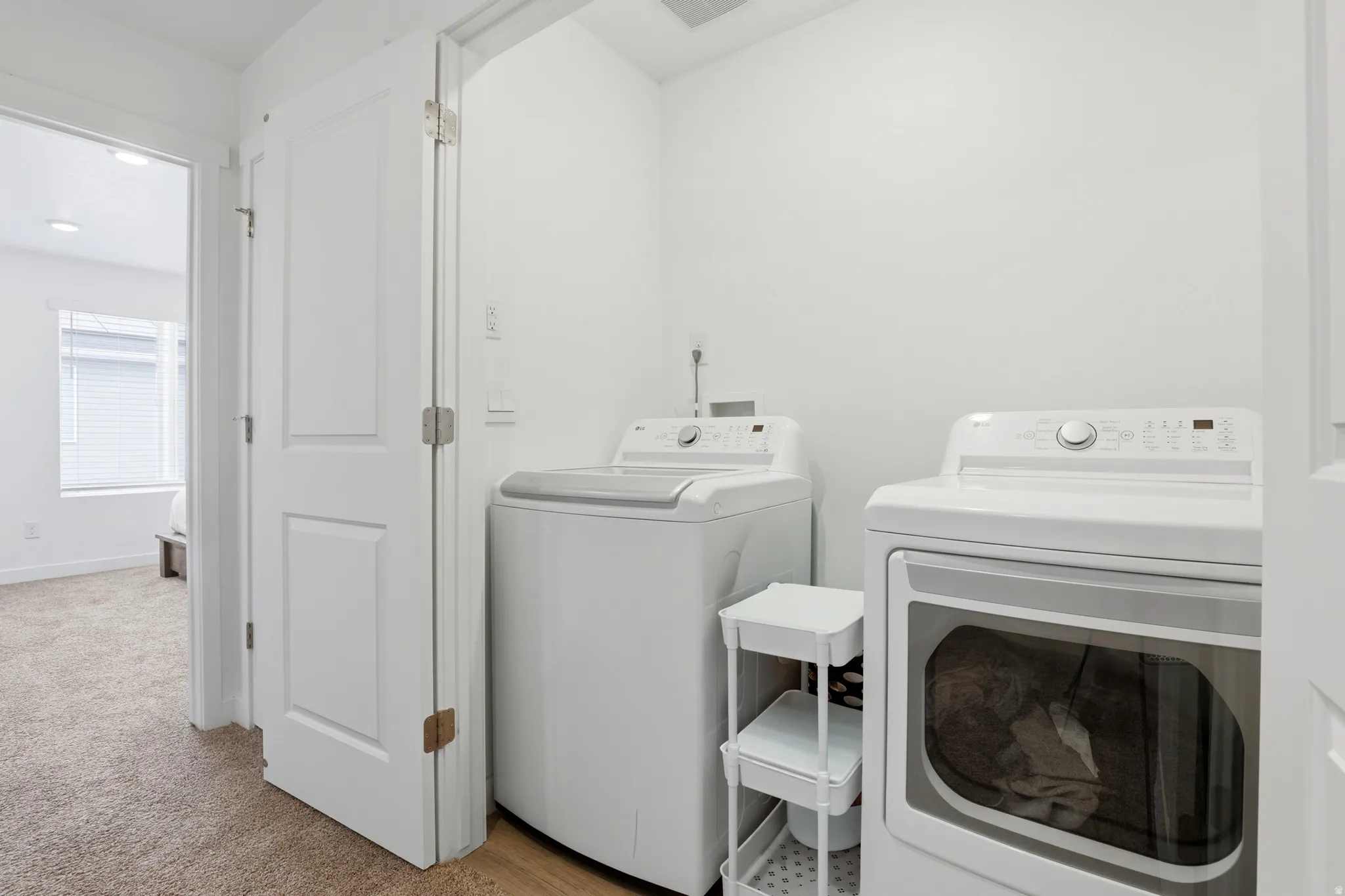 Dedicated laundry area featuring wood-finish flooring, white walls, and a white paneled door
