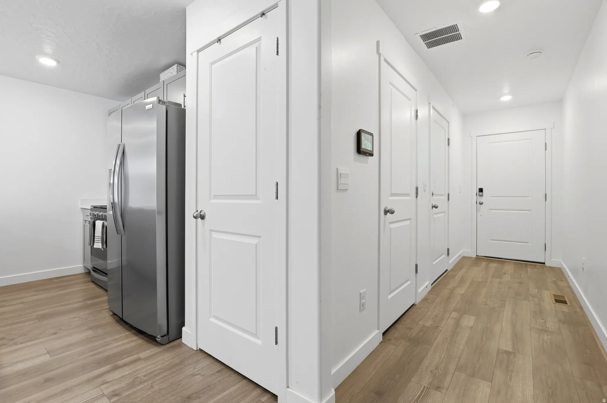 Corridor featuring wood-finish flooring, recessed lighting, and a series of paneled doors