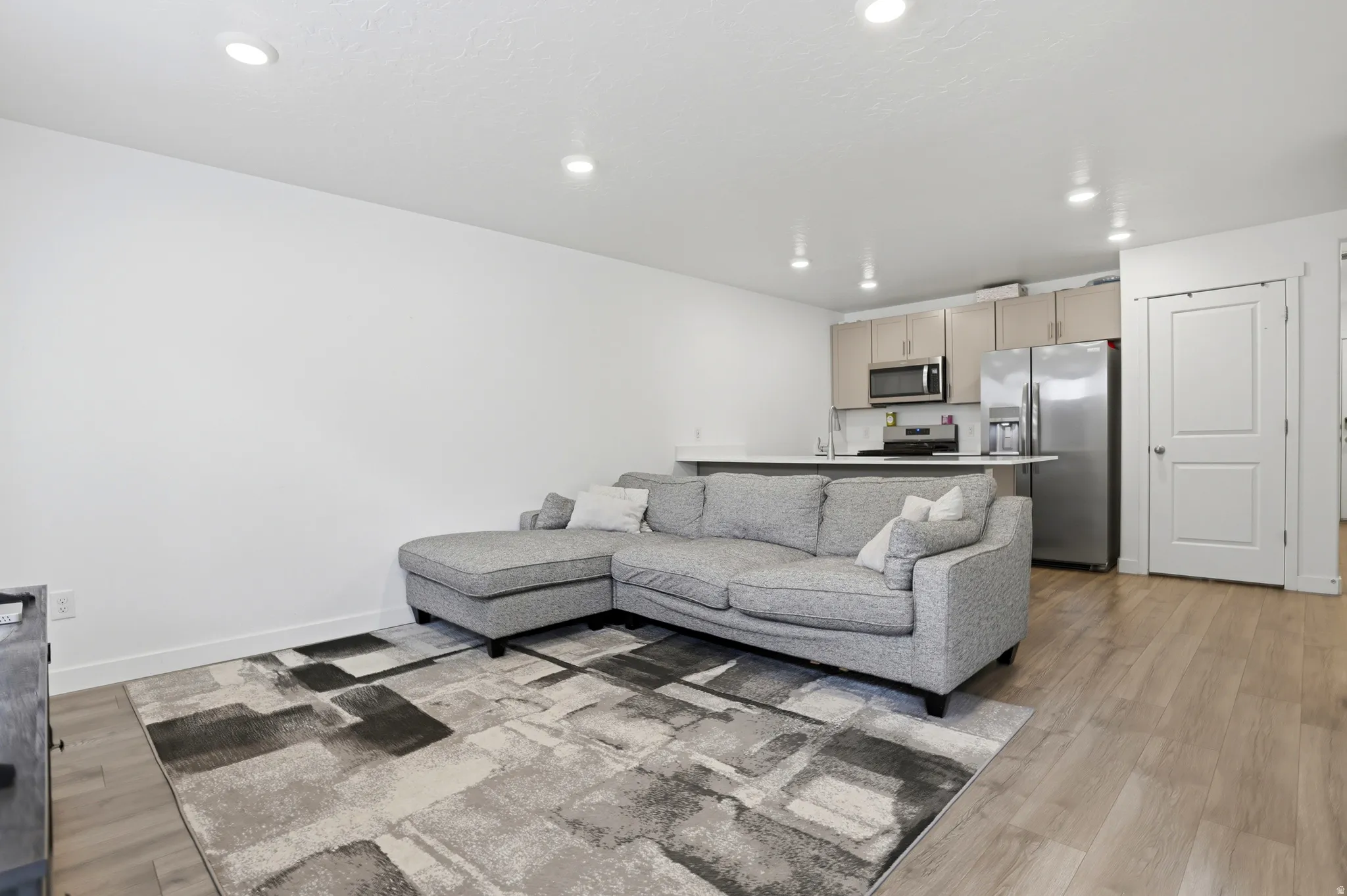 Open-concept living space featuring wood-finish flooring, recessed lighting, and white walls