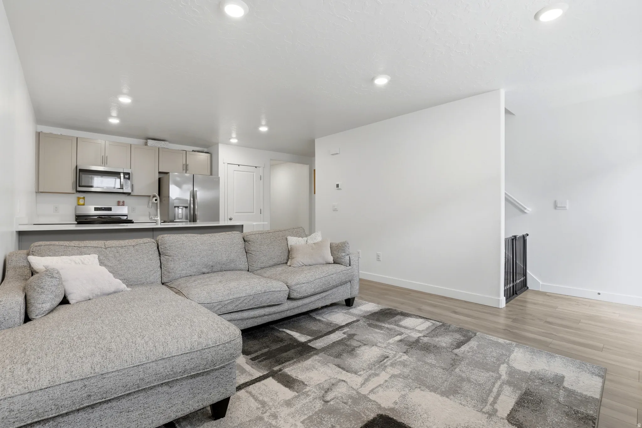 Open-concept living area featuring wood-finish flooring, recessed lighting, and a modern kitchen