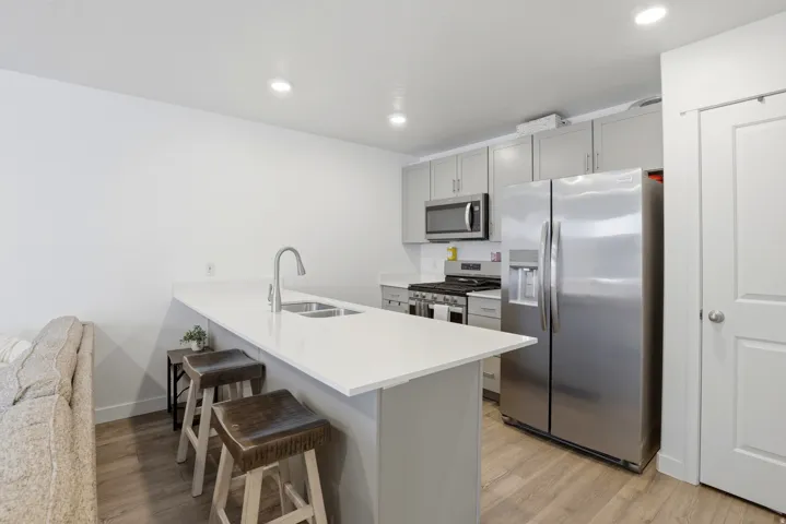 Modern kitchen featuring a breakfast bar with seating, stainless steel appliances, light gray cabinetry, and recessed lighting