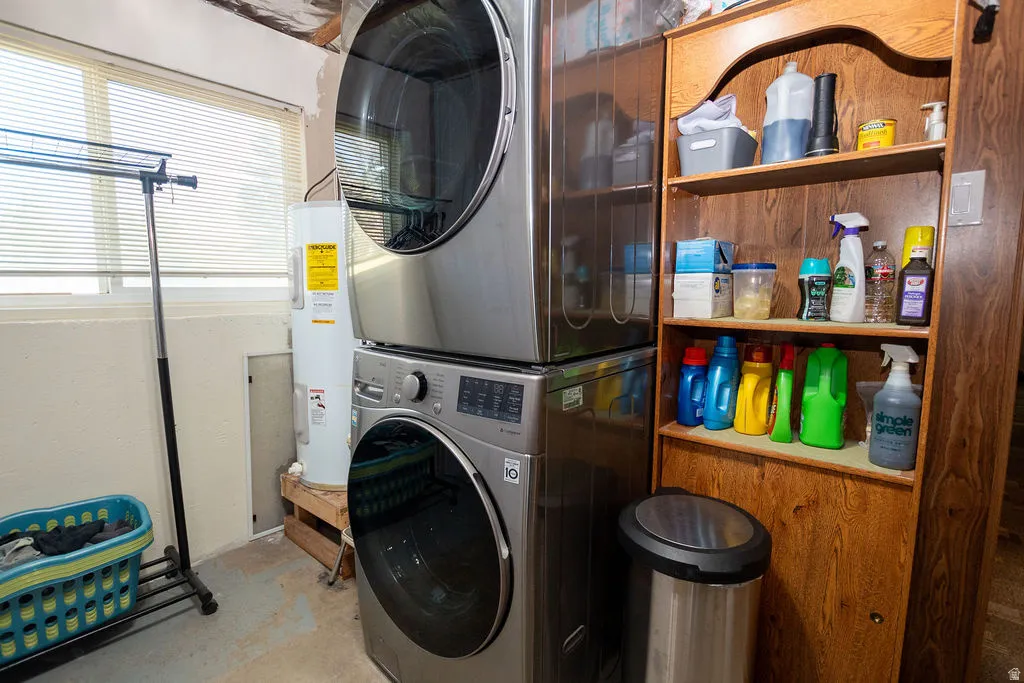 Laundry area featuring a stackable washer and dryer, a water heater, and wood-finish shelving