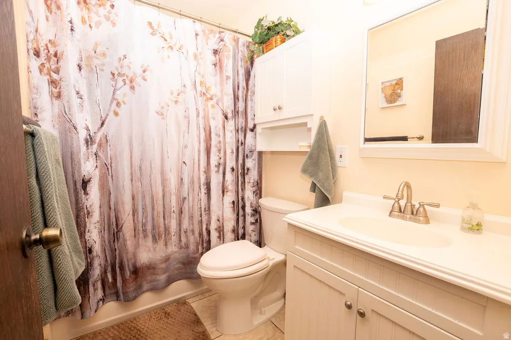 Bathroom featuring a white vanity with integrated sink, brushed nickel faucet, wall-mounted mirror, and white over-toilet cabinetry