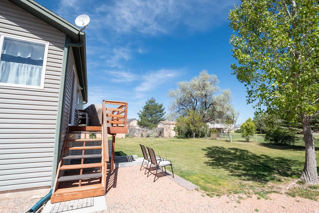 Expansive backyard featuring a manicured lawn, established trees, and a gravel patio area