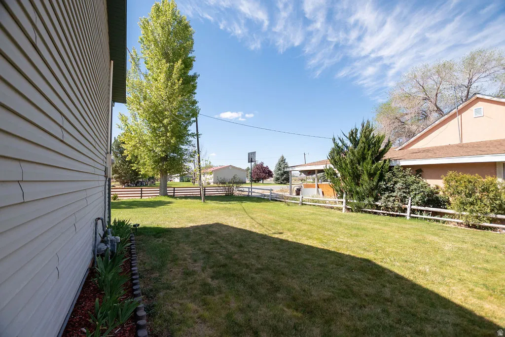 Expansive backyard featuring a manicured lawn, established landscaping, and a wood-slat fence