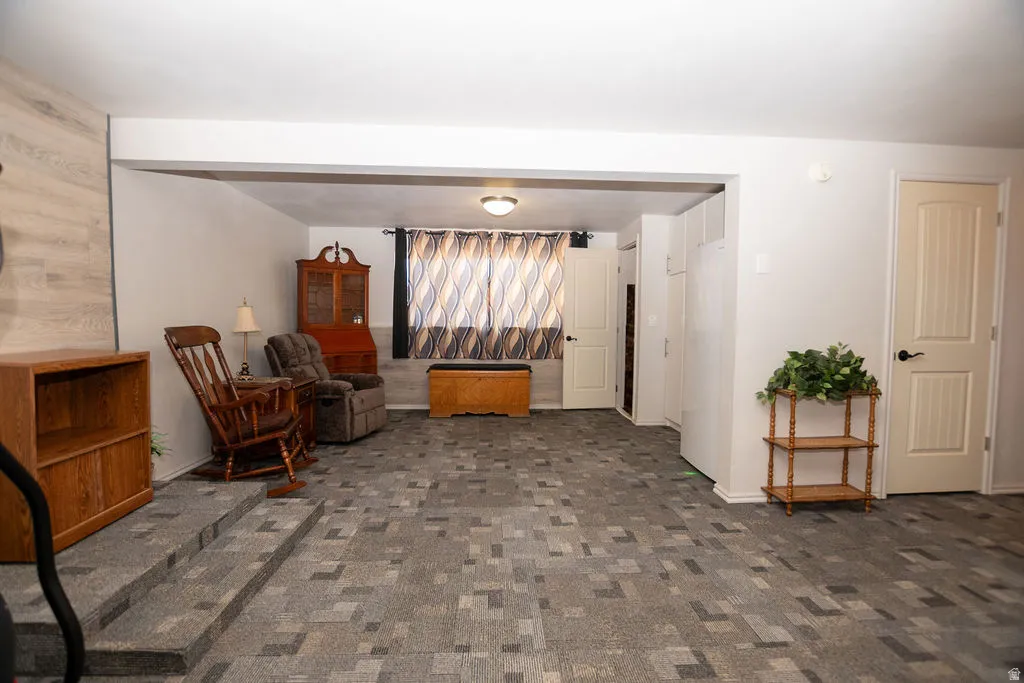 Spacious room featuring patterned carpet flooring, a stepped transition, and neutral wall tones