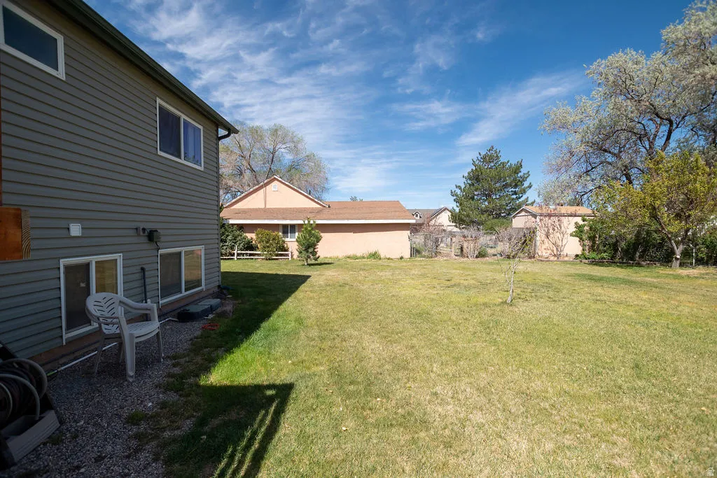 Spacious backyard featuring a large grass area and mature perimeter trees