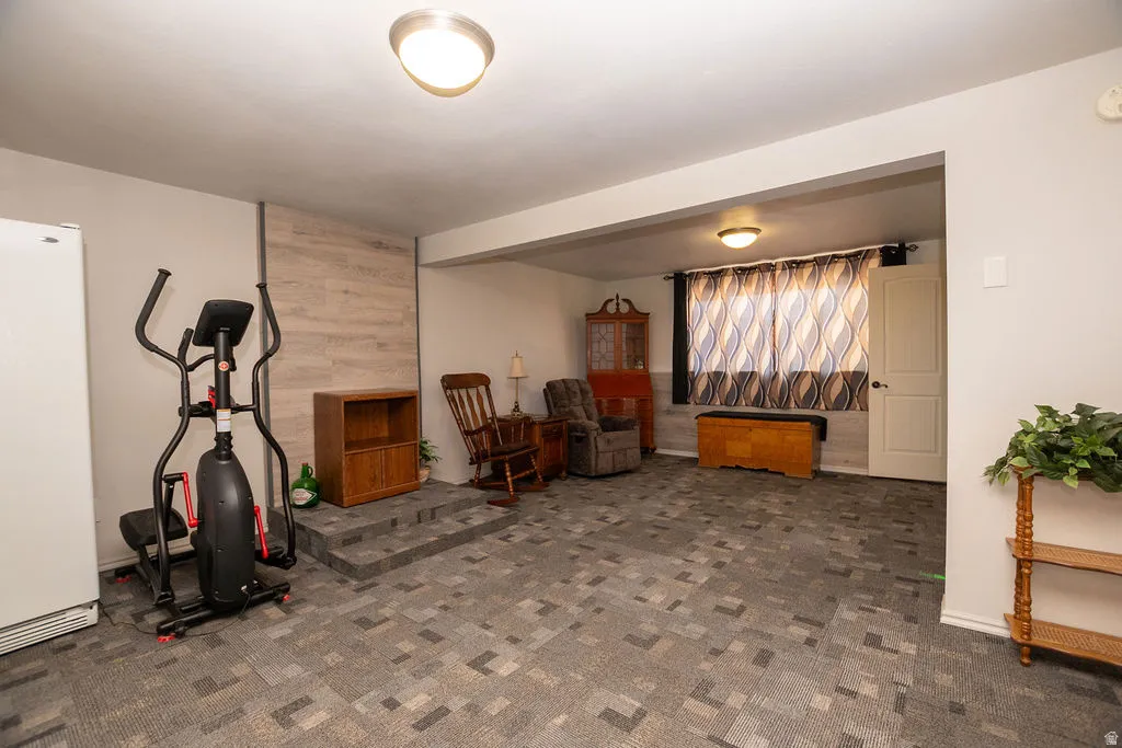 Lower level featuring patterned carpet flooring, recessed wall paneling, and an exposed structural beam