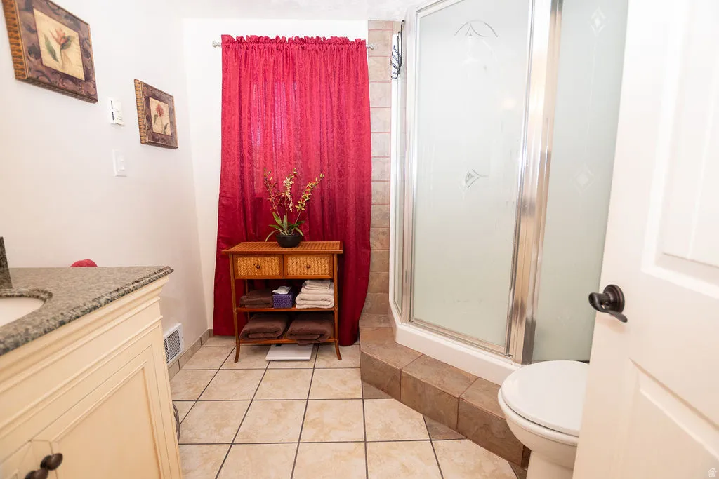Bathroom featuring a corner shower enclosure with frosted glass, a white toilet, and tile flooring