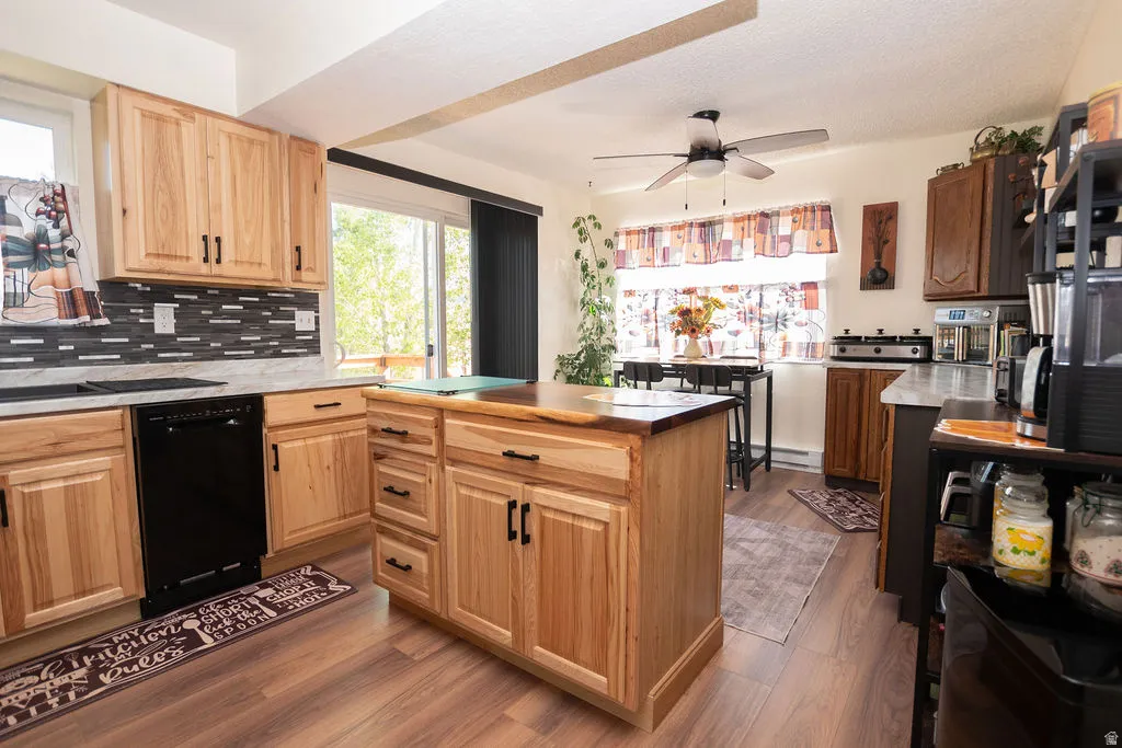 Kitchen featuring light wood cabinetry with black hardware, a contrasting dark mosaic tile backsplash, and wood-finish flooring