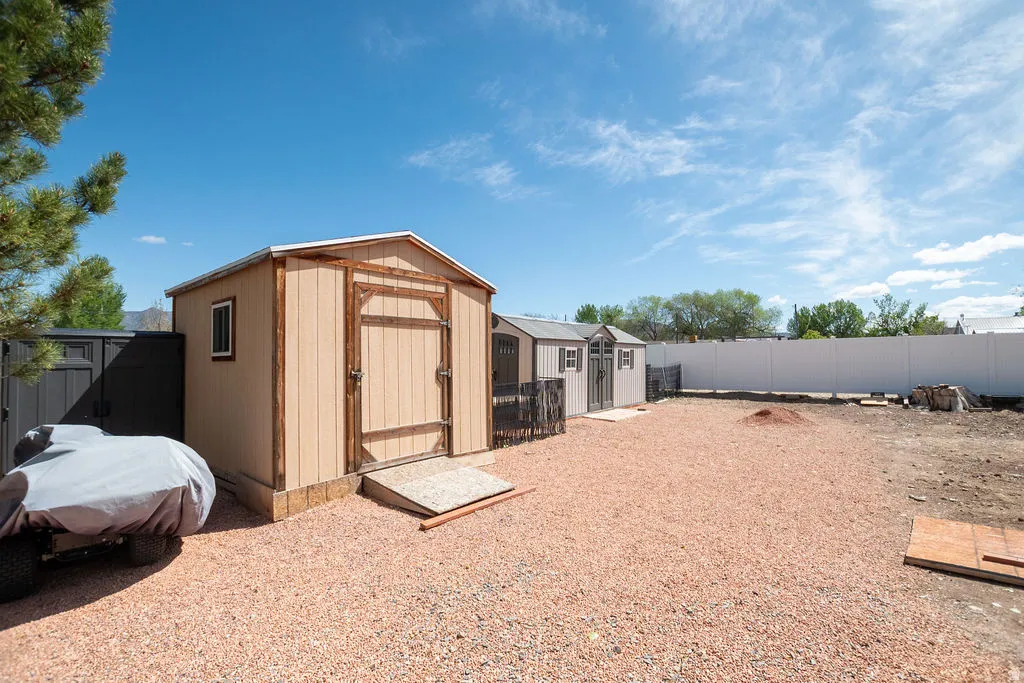 Expansive gravel-covered yard featuring three storage sheds
