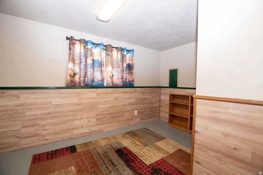 Room featuring light wood-finish wainscoting with a dark green trim, light-toned walls, and a fluorescent ceiling light