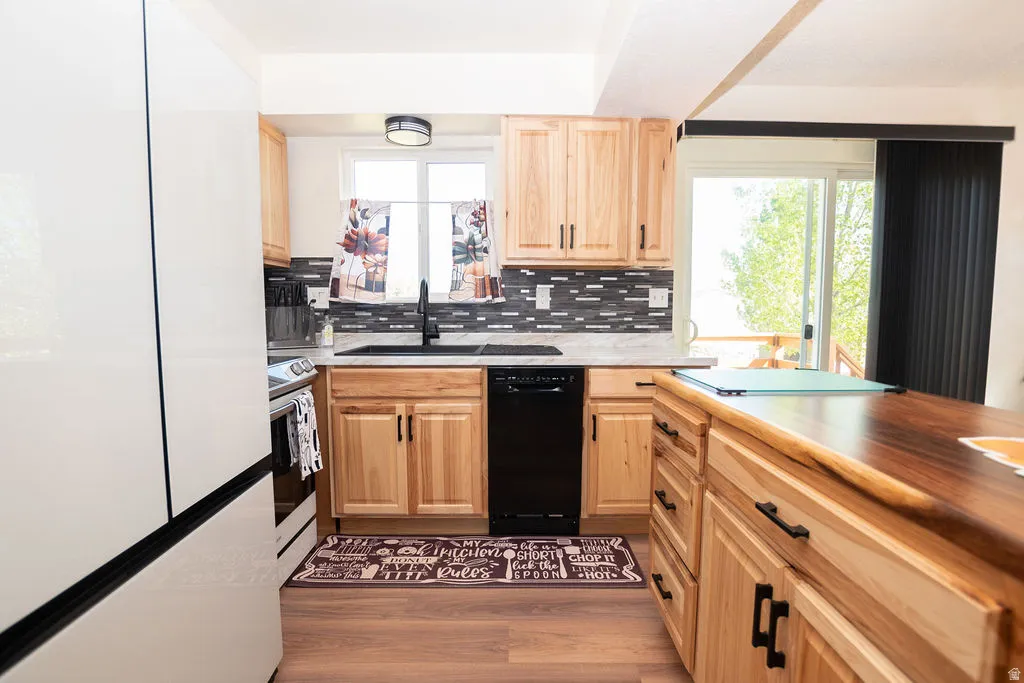Kitchen featuring light wood-finish cabinetry, a patterned tile backsplash, and dark hardware