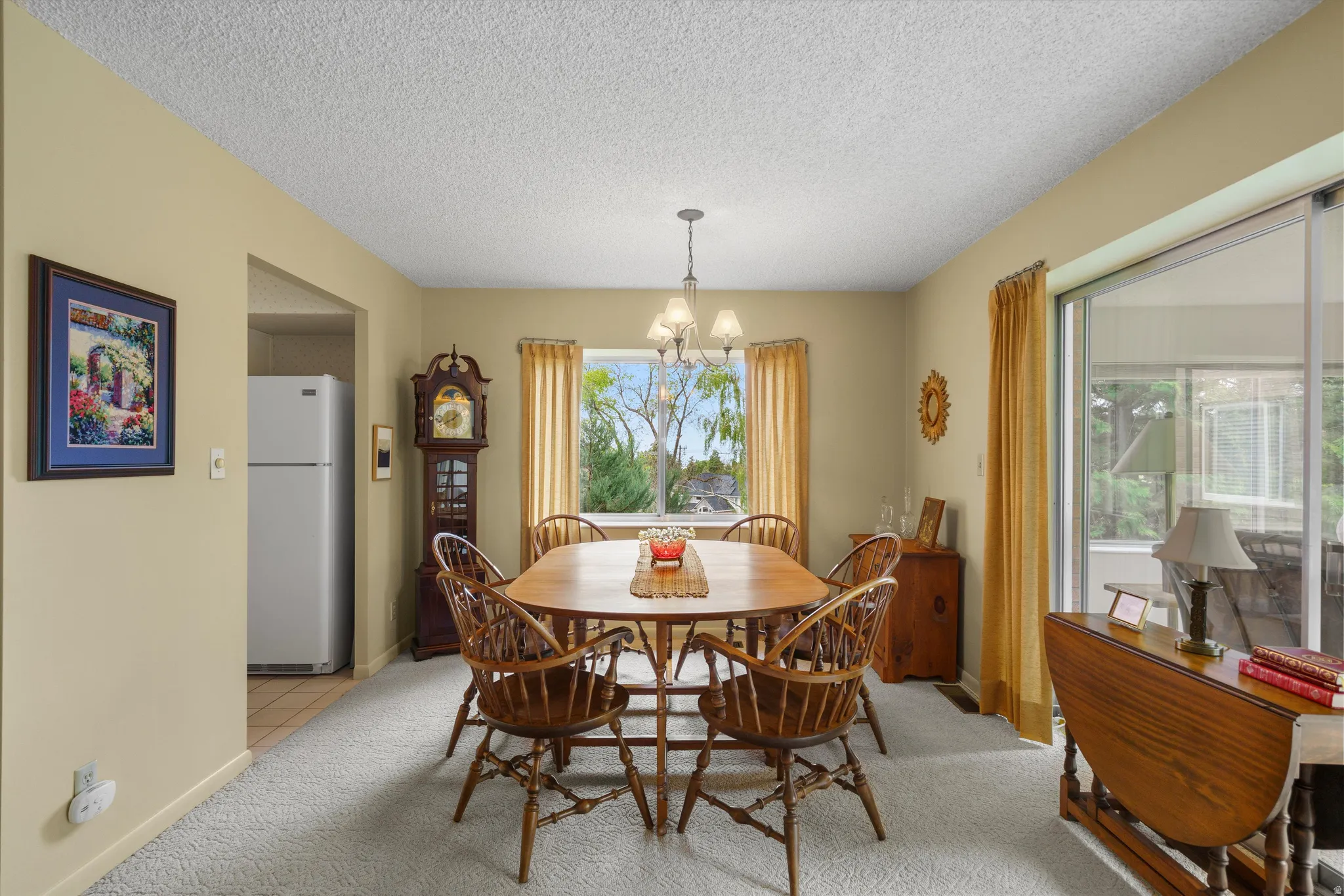 Dining area featuring neutral wall paint, white textured ceiling, light-colored carpet flooring, and a chandelier light fixture