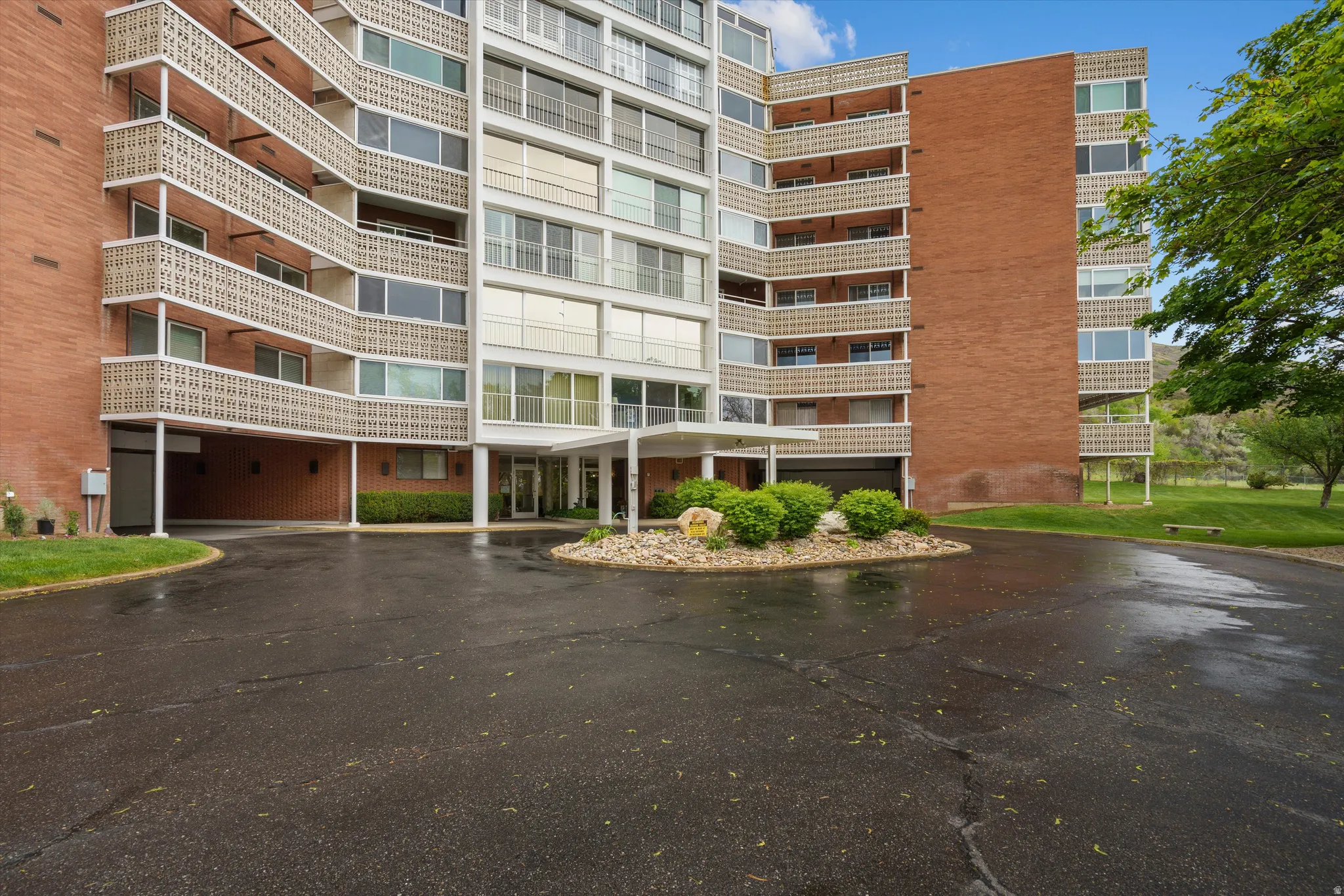 Multi-story apartment building featuring a brick facade, white window trim, and individual balconies with decorative railings