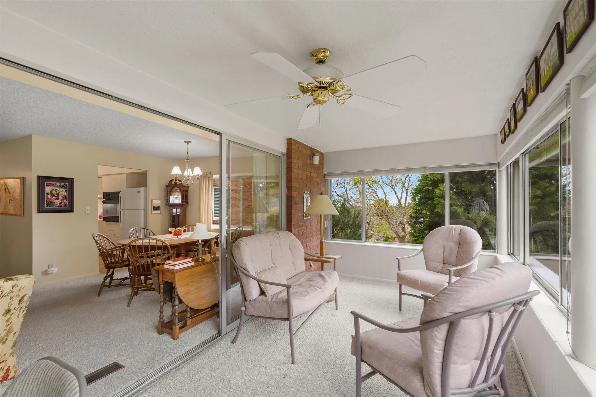 Sunroom featuring wall-to-wall windows, a ceiling fan fixture, and light-colored carpeting
