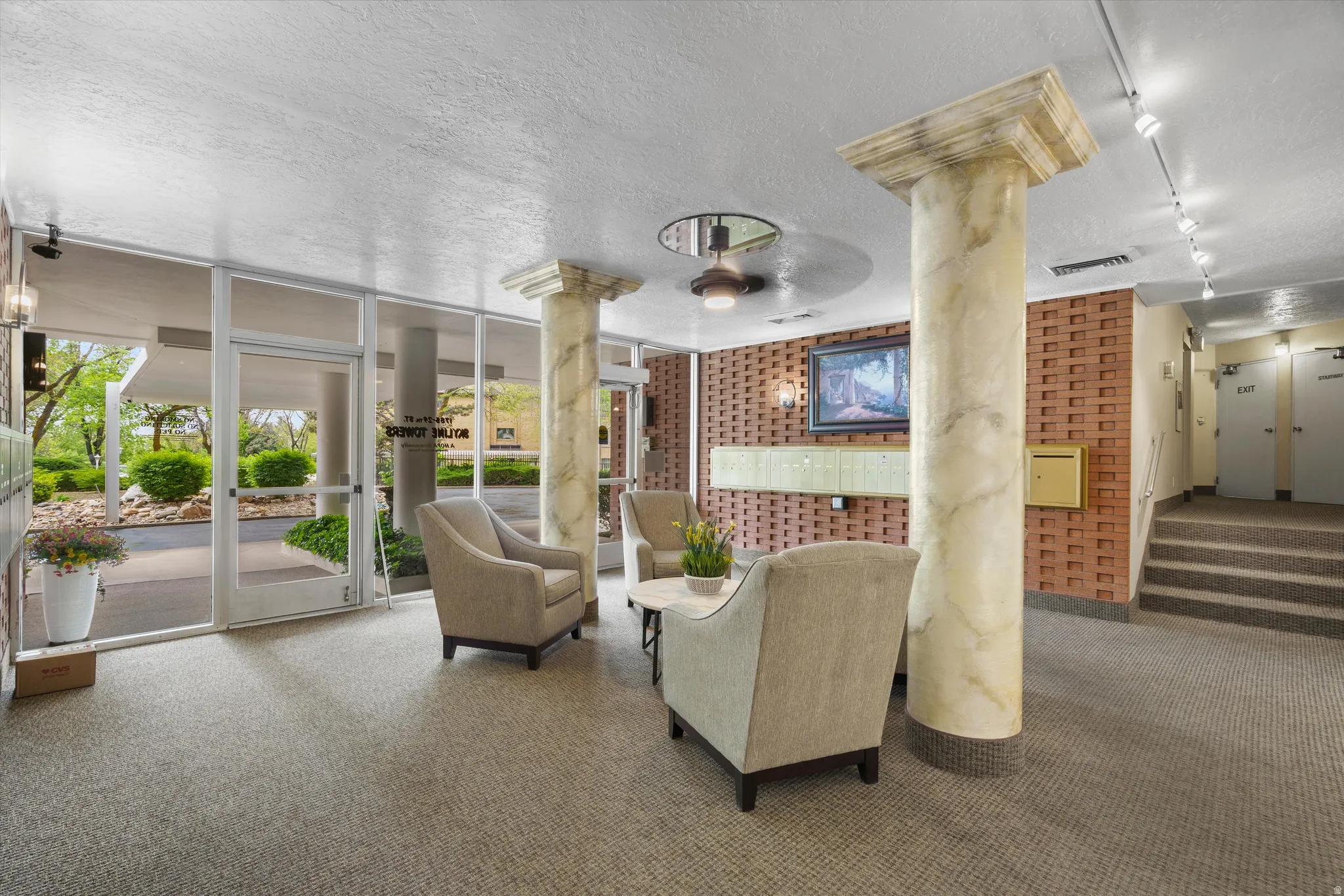 Building entry featuring a glass door, floor-to-ceiling windows, and two marble-look columns