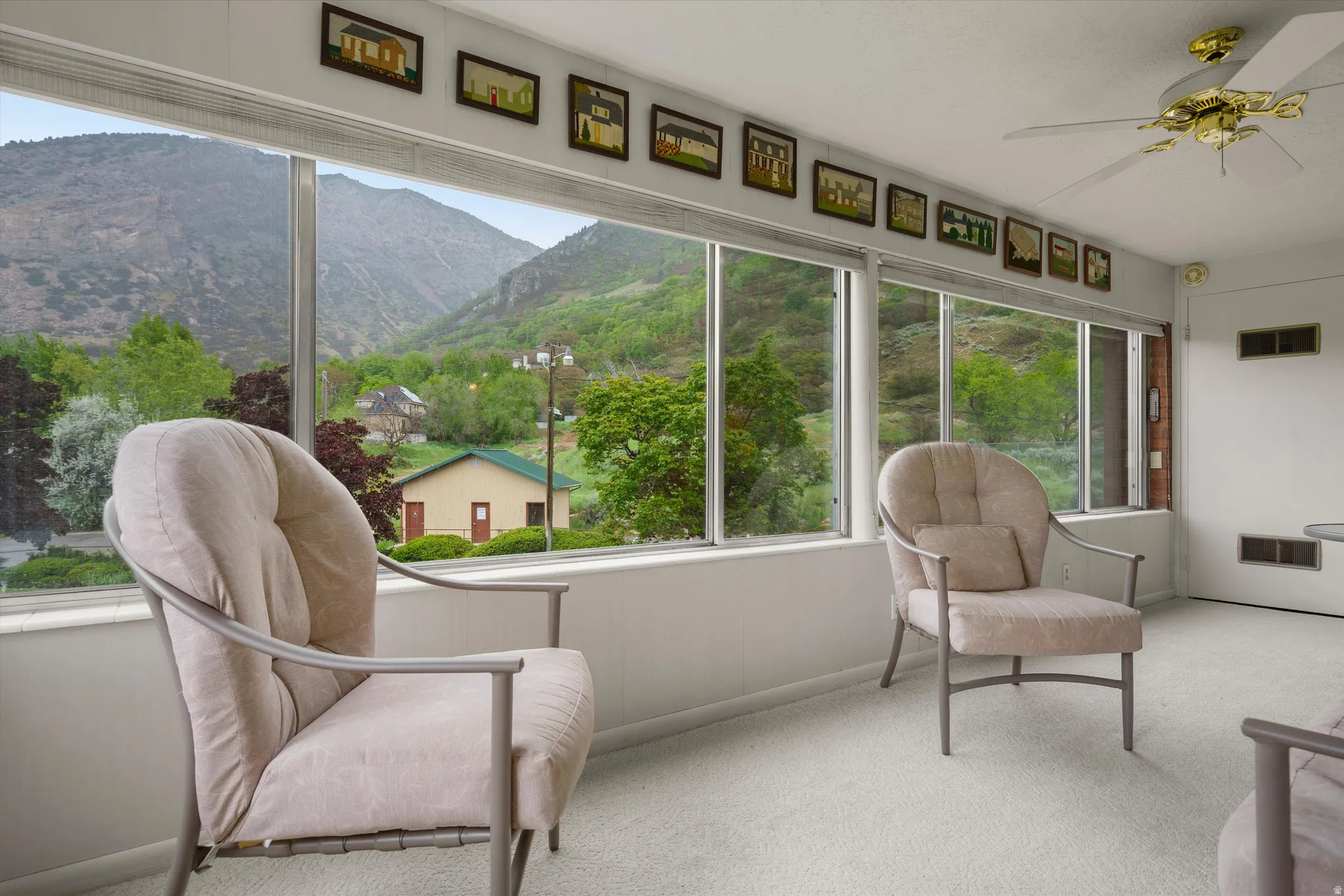 Sunroom with expansive window wall, light-toned carpeting, white ceiling, and a ceiling fan