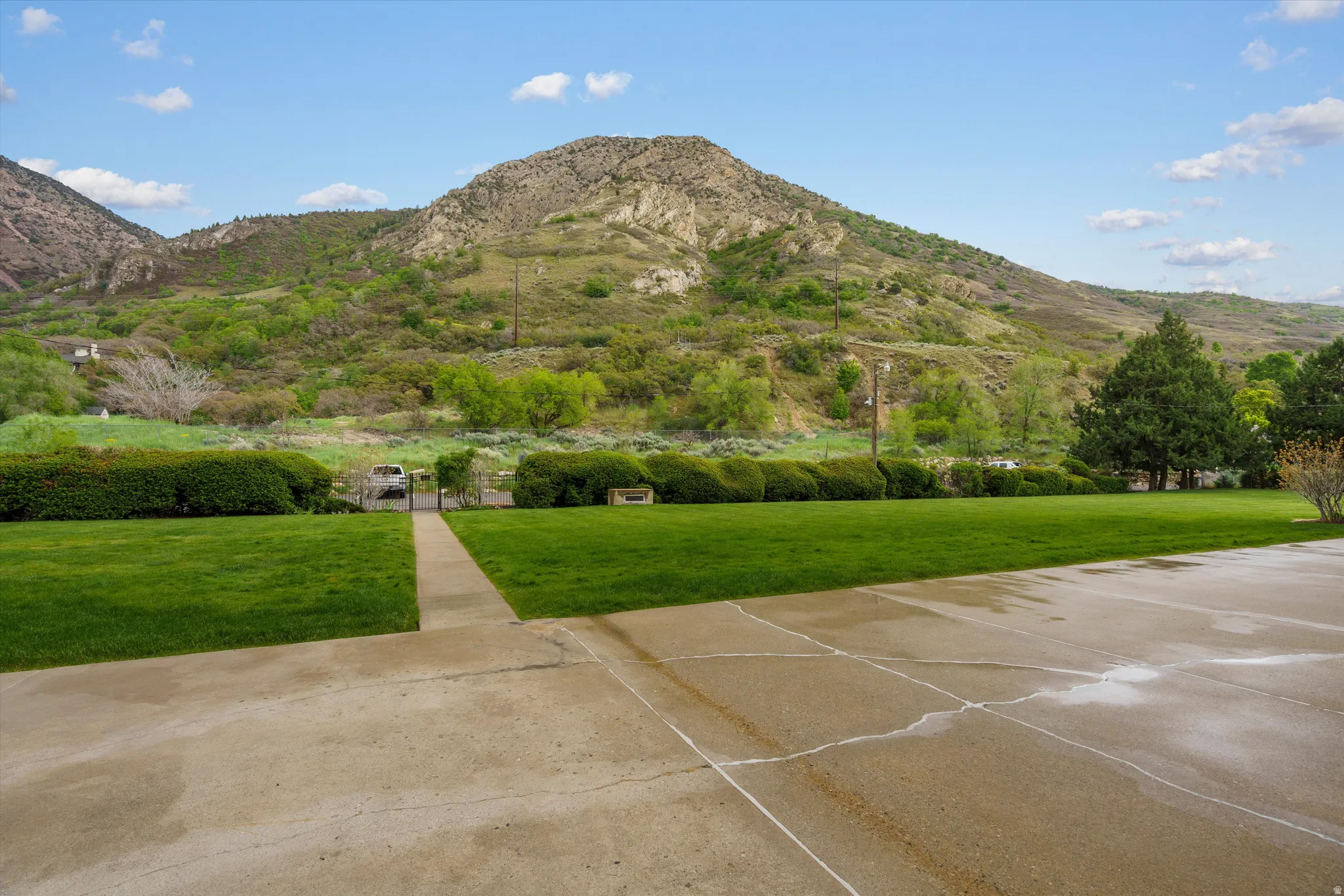 Expansive concrete driveway and walkway leading to a manicured lawn
